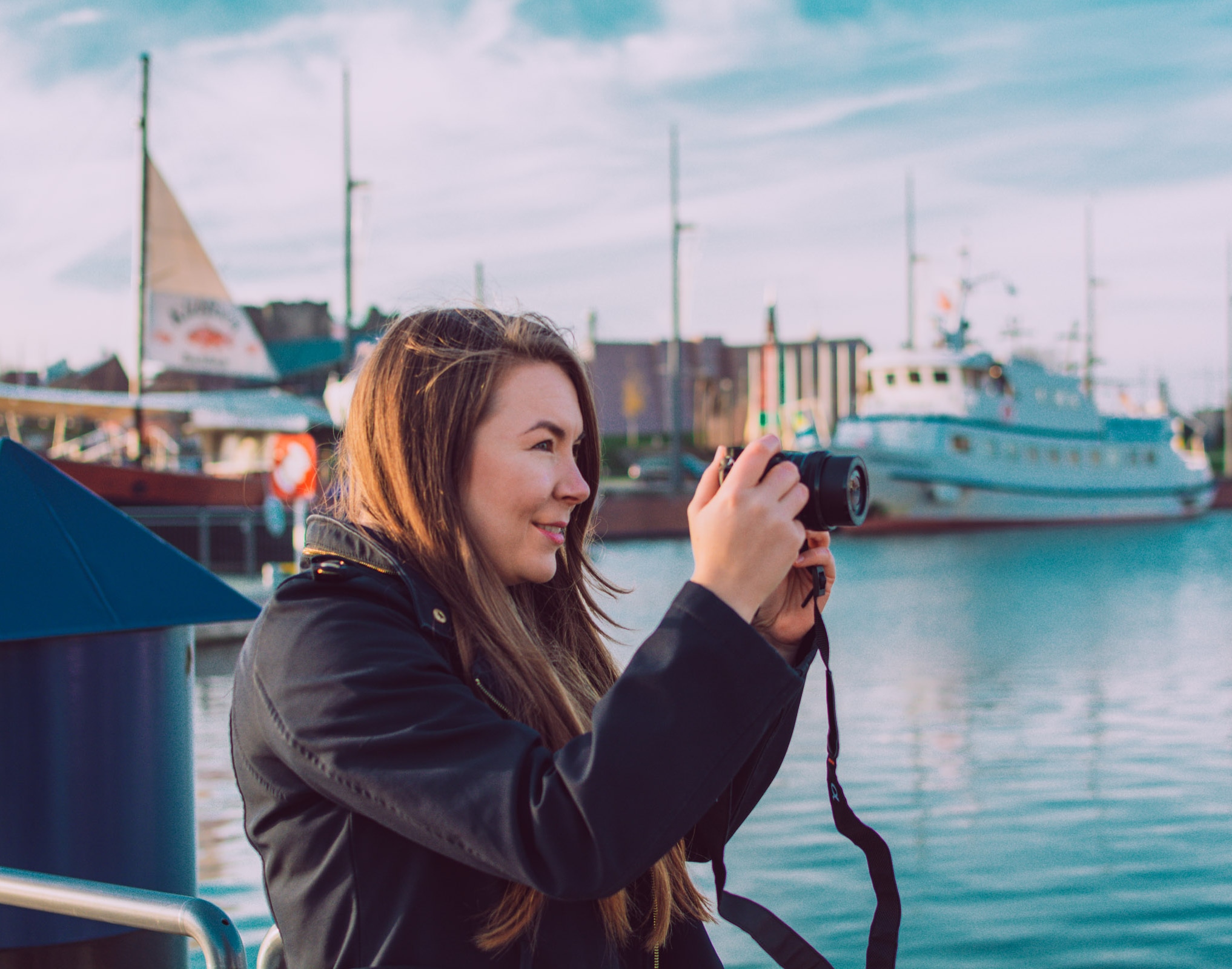 Sarah taking a photo with her Camera in front of sailing boats