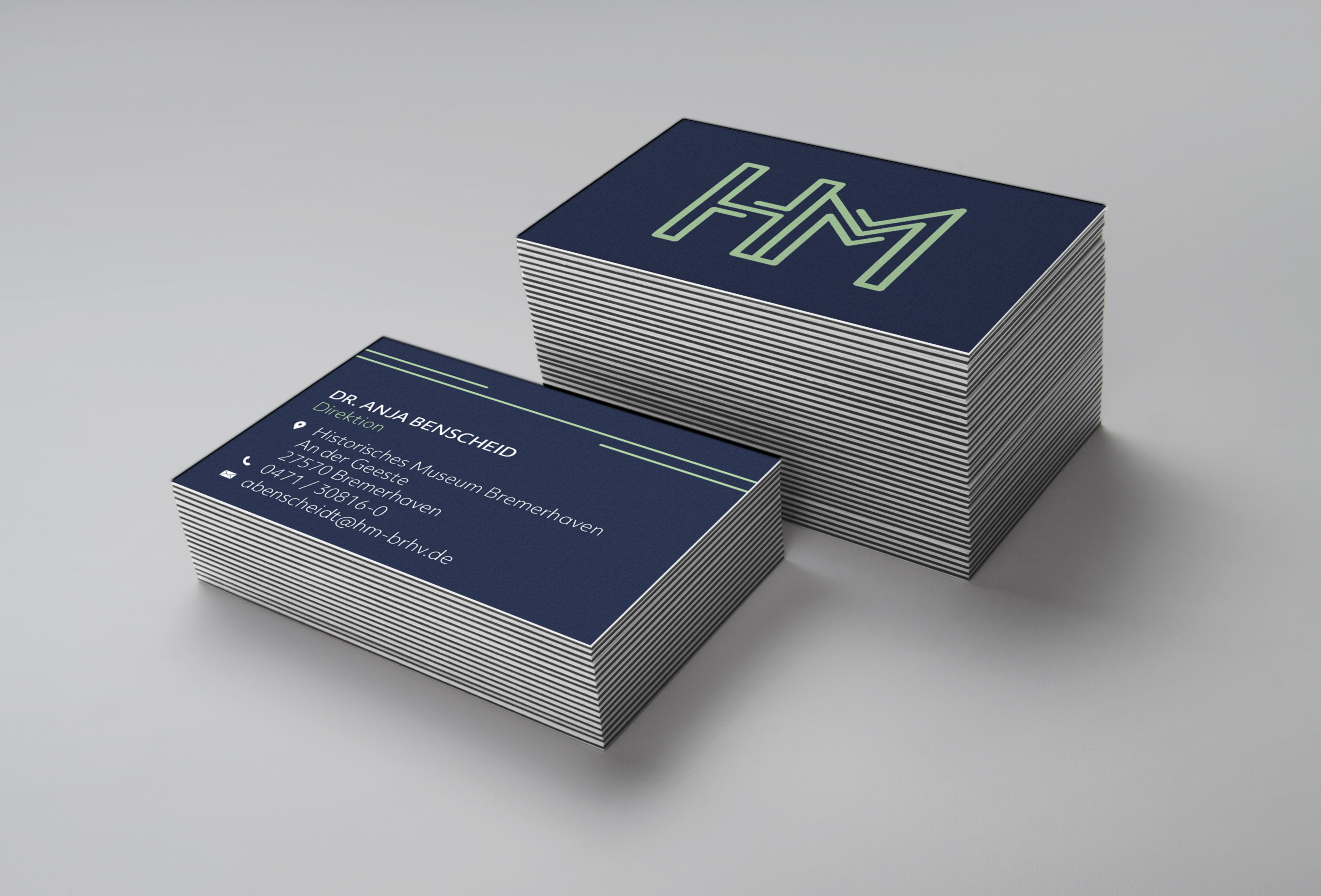 businesscard stack, cards in dark blue with white text and lime-colored logo