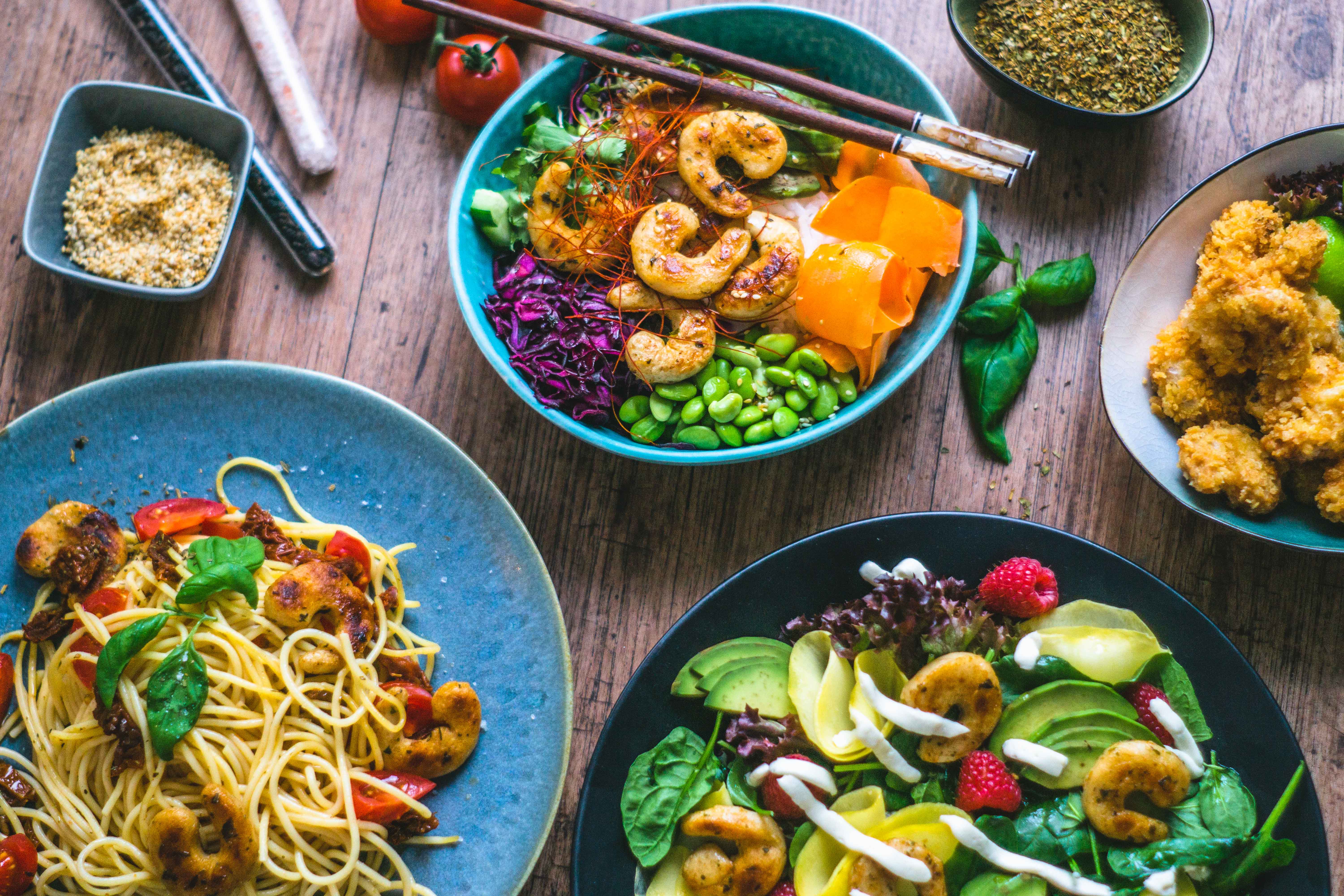 Dropshot of multiple shrymp dishes: asian bowl with edamame, veggies and shrymps, a bowl of pasta with shrymps and tomatoes and a bog green summer salad with shrymps, mango and raspberries