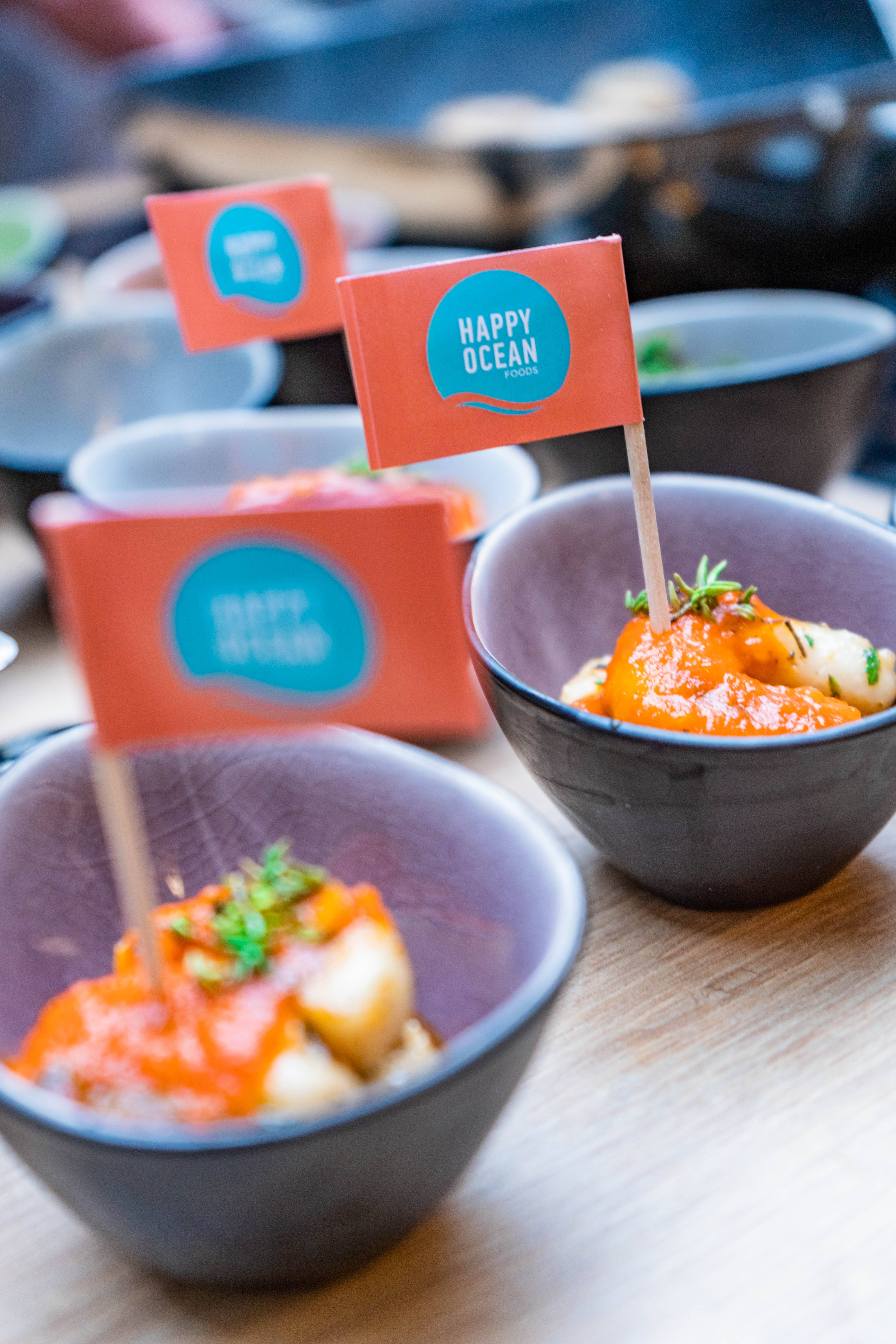 multiple small bowls with shrymps and tomato sauce all with a tiny branded flag