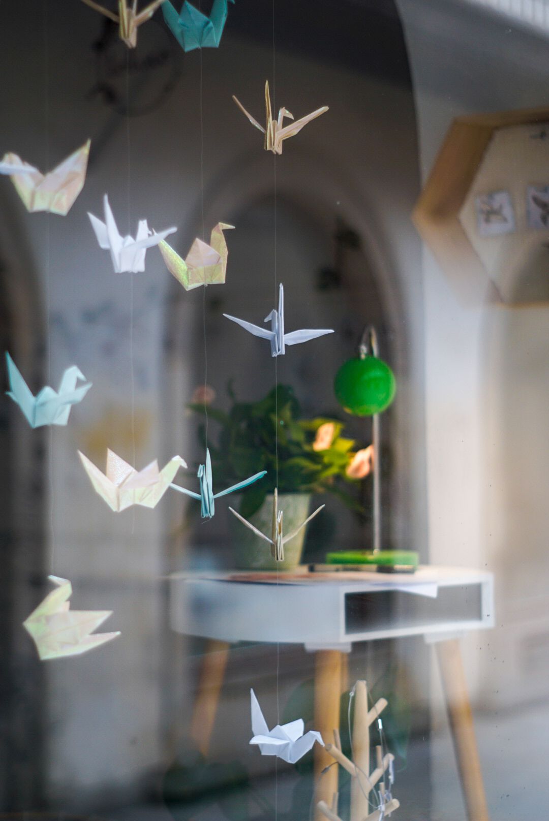 photo inside of a window with colorful origami birds