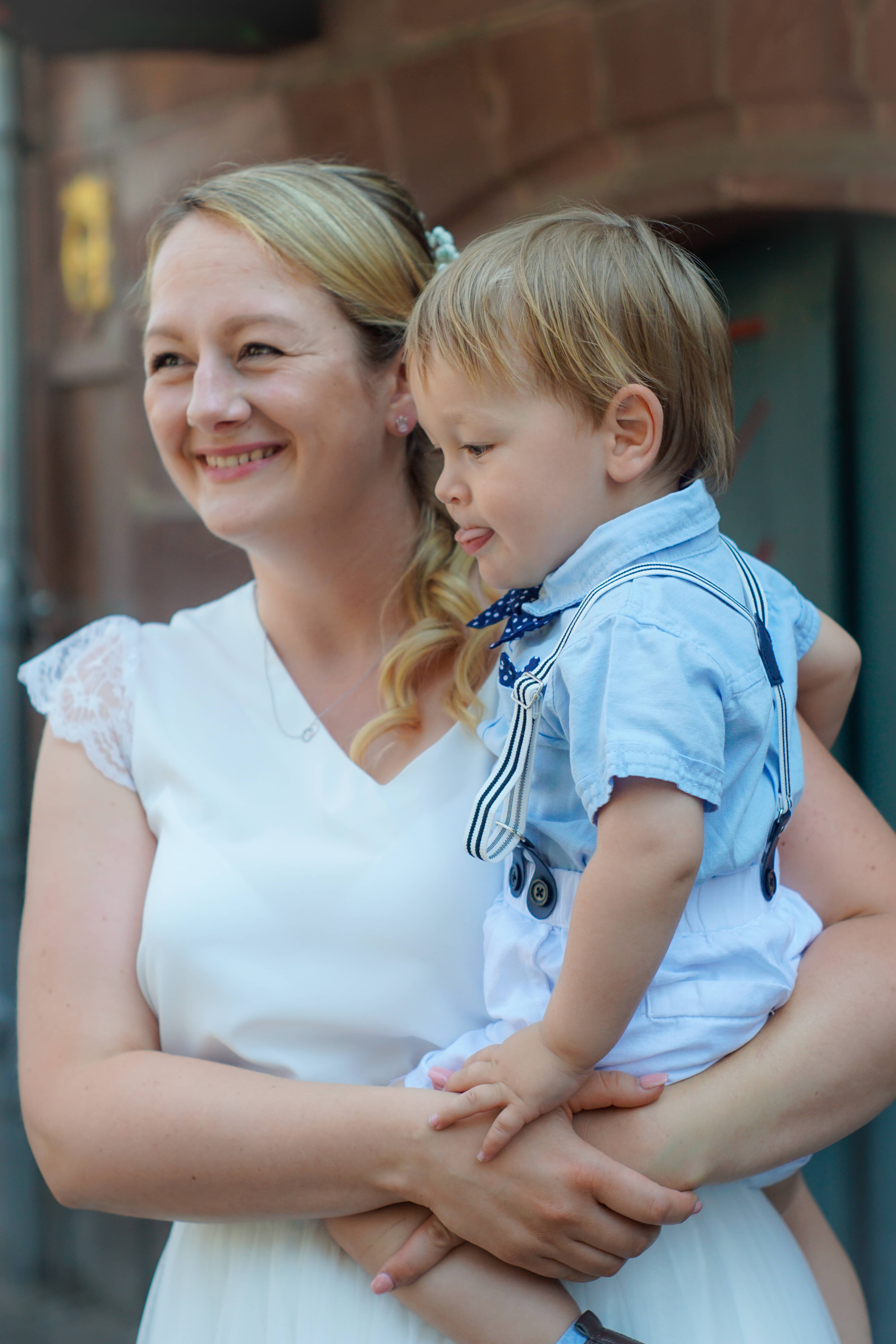 Happy bride in a casual white dress with her son on her arm