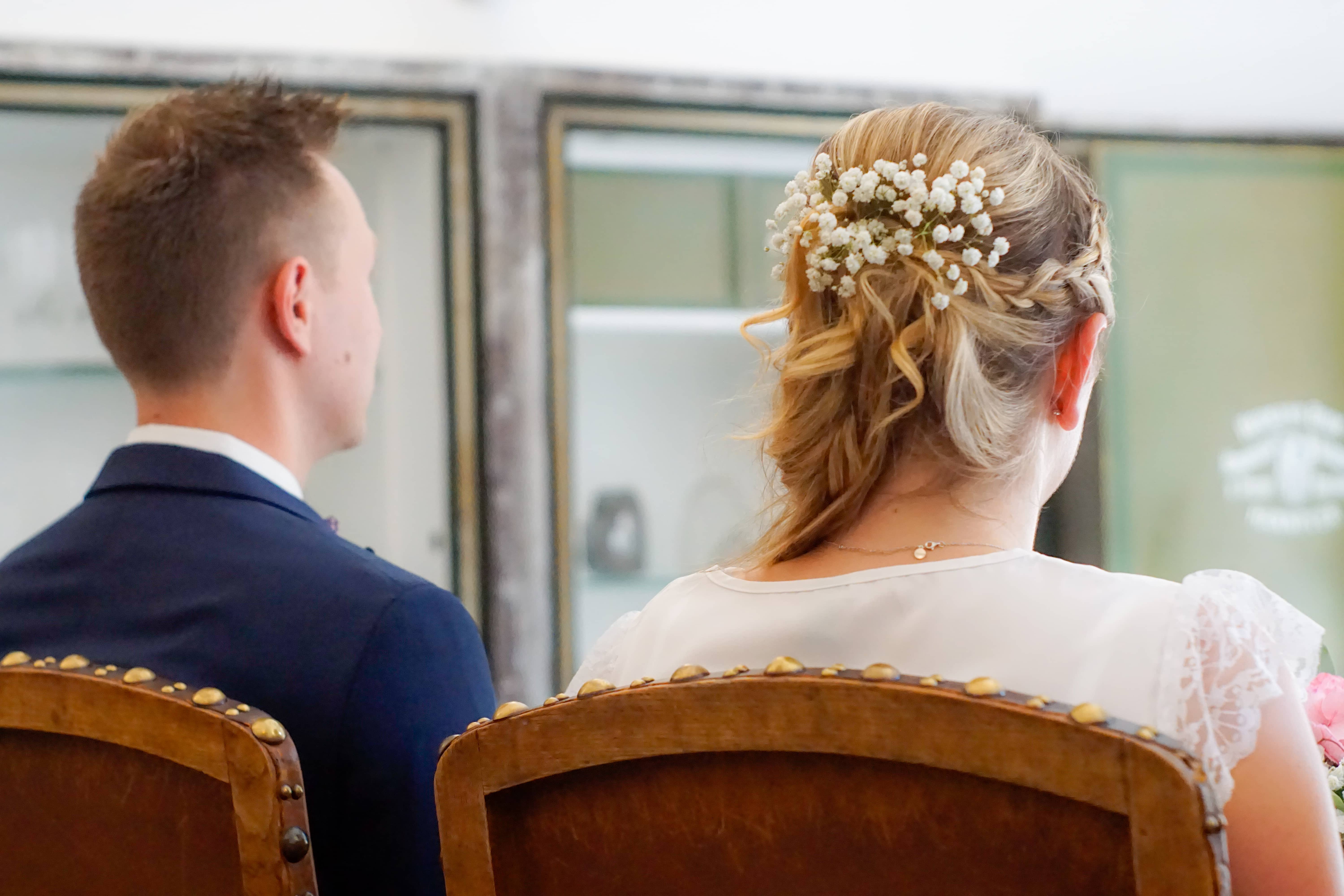 Behind view of groom and bride with flowers in her hair at their civil wedding